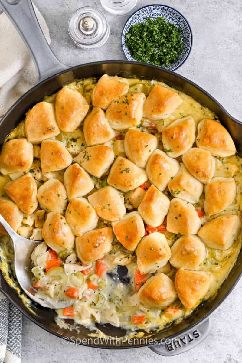 chicken and biscuits in a pan with a serving spoon.