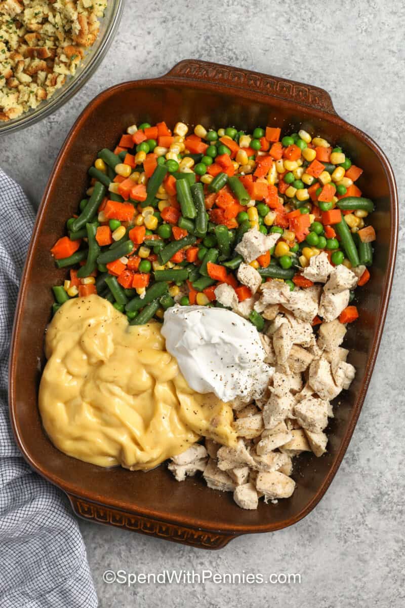 adding ingredients to dish to make Chicken Stuffing Casserole.