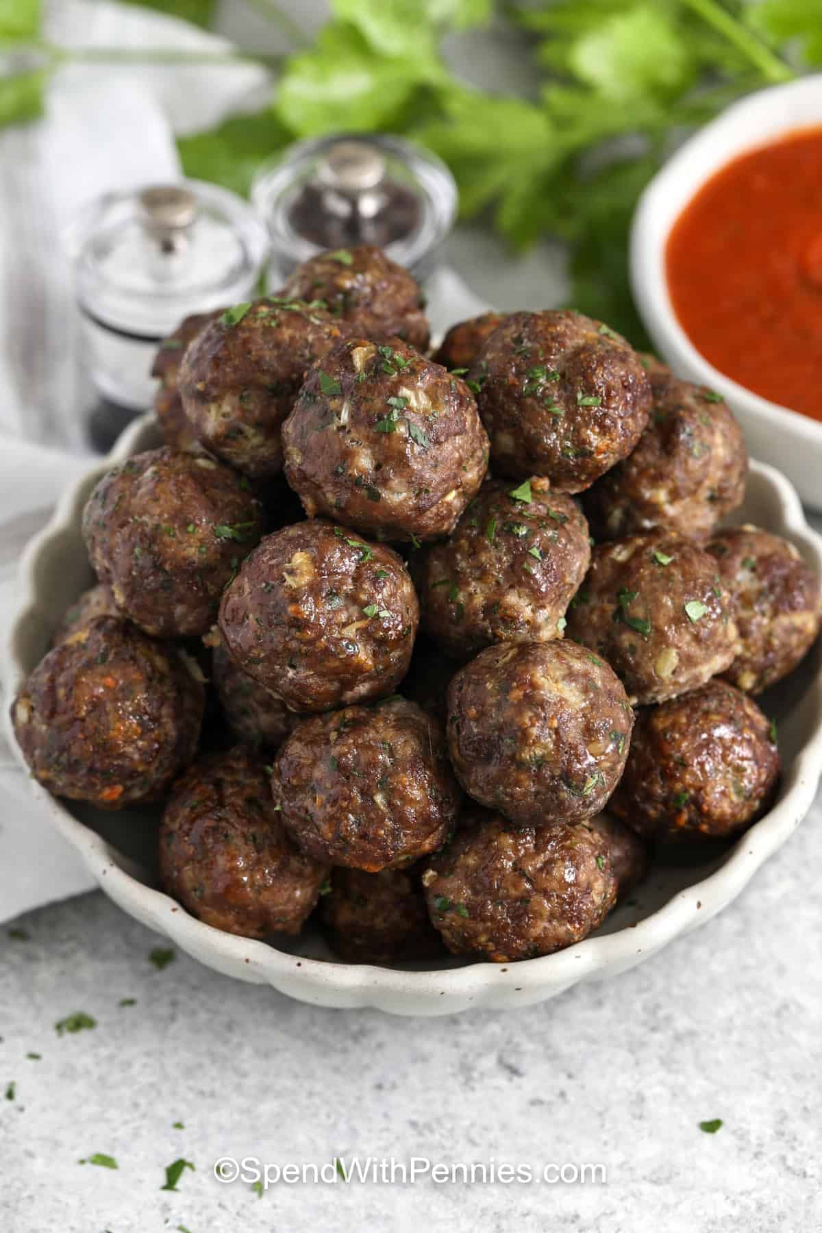 This easy meatball recipe is a classic comfort food staple for busy home cooks. Ground beef and pork are gently mixed with seasoned breadcrumbs, milk, onion, parsley, Parmesan, egg, and garlic powder, then baked until tender and cooked through. Serve these homemade meatballs with marinara sauce, tuck them into subs, or keep a freezer bag ready for fast pasta nights. #spendwithpennies plated dish of Easy Meatball Recipe