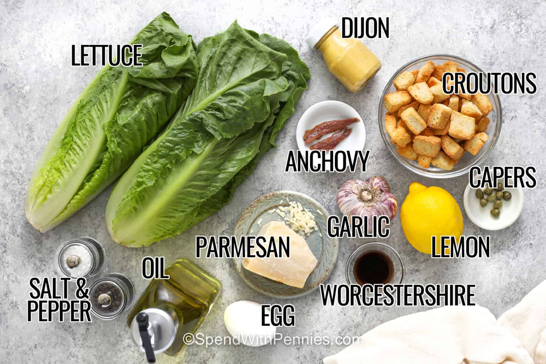 This easy Caesar salad recipe delivers plenty of texture with crisp romaine, crunchy croutons, shredded Parmesan, and thick creamy dressing. A quick blender method makes the homemade Caesar dressing easy, while anchovies, capers, fresh lemon, and garlic add savory depth. Add grilled chicken for a simple meal or serve it alongside an Italian dinner. Save this salad recipe for your next weeknight meal or gathering. #spendwithpennies lettuce , dijon , anchovy , croutons , capers , lemon , Worcestershire sauce , garlic , parmesan , egg , oil , salt and pepper with writing to make Caesar Salad.