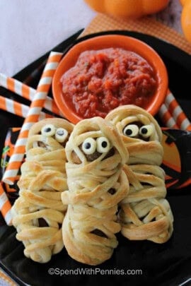 Meatball Mummies with marinara on black plate.