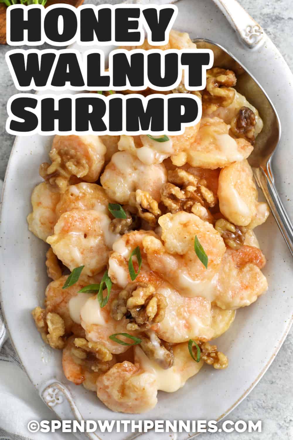 This honey walnut shrimp recipe has everything a takeout craving needs, from lightly battered shrimp to creamy honey sauce and sweet candied walnuts. Cornstarch and foamy egg whites create a crisp coating without a heavy breading, while fresh lemon balances the rich sauce. It is an impressive shrimp dinner made with familiar ingredients and simple techniques. Pin this crispy shrimp recipe for later. #spendwithpennies tender Honey Walnut Shrimp with a title.