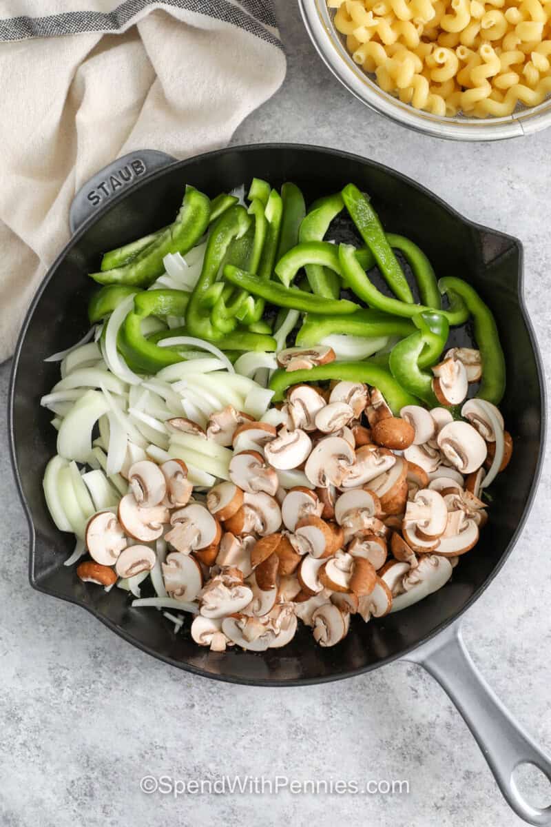 adding vegetables to pan to make Philly Cheesesteak Casserole.