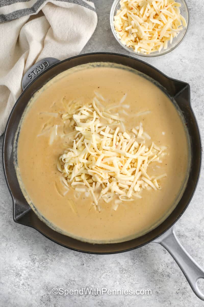 adding cheese to pan to make sauce for Philly Cheesesteak Casserole.