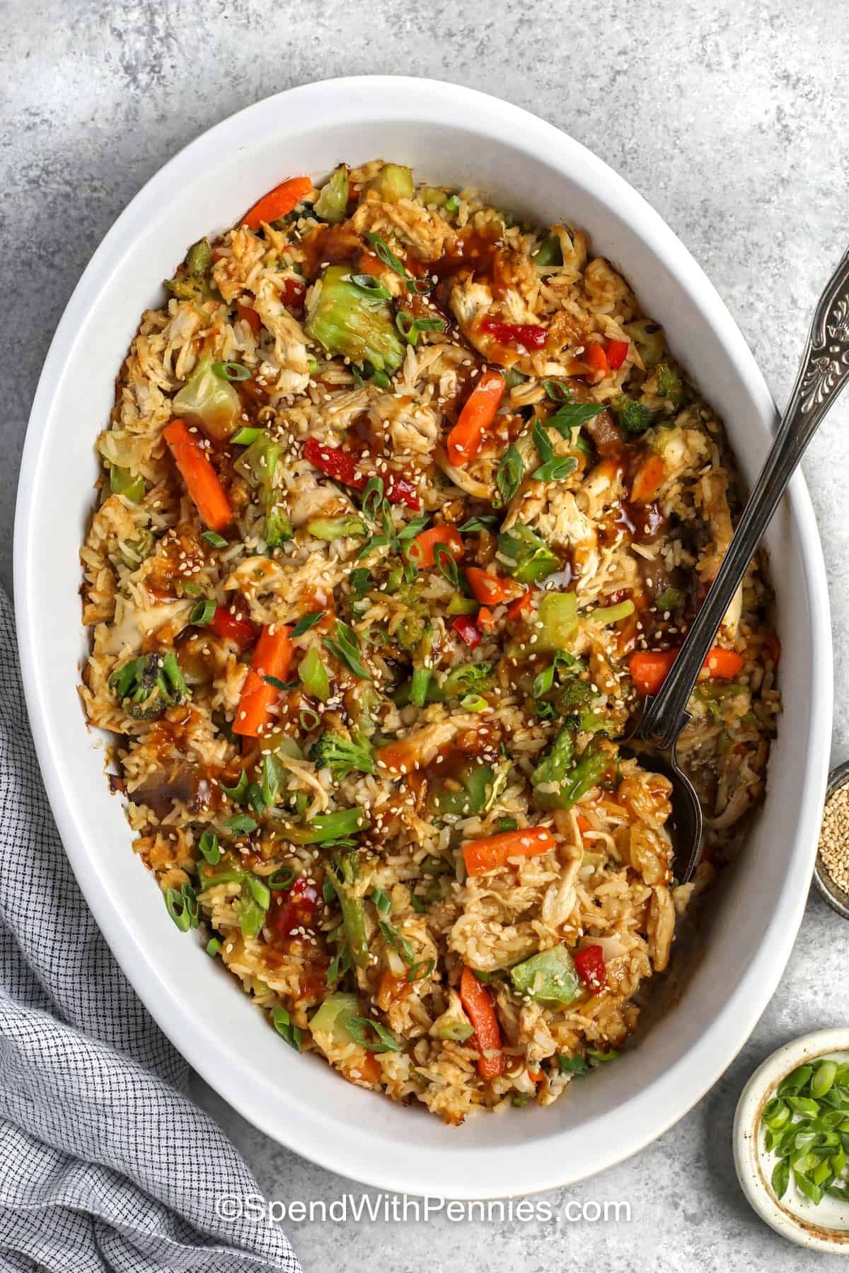 Teriyaki chicken casserole is an easy way to turn cooked chicken, fluffy rice, and frozen stir-fry vegetables into a complete family dinner. A homemade teriyaki sauce made with soy sauce, fresh ginger, garlic, brown sugar, and citrus coats every bite with sweet and savory flavor. Everything bakes together in a 9x13-inch dish for a comforting meal with minimal chopping. Save this easy casserole for a busy weeknight dinner. #spendwithpennies dish of Teriyaki Chicken Casserole.