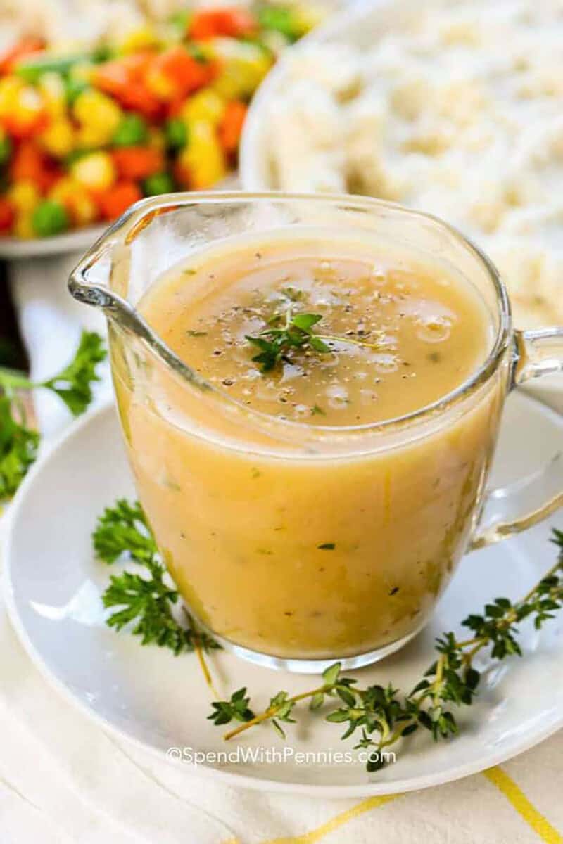 jar pf Turkey Gravy Recipe with plates of mashed potatoes and vegetables.