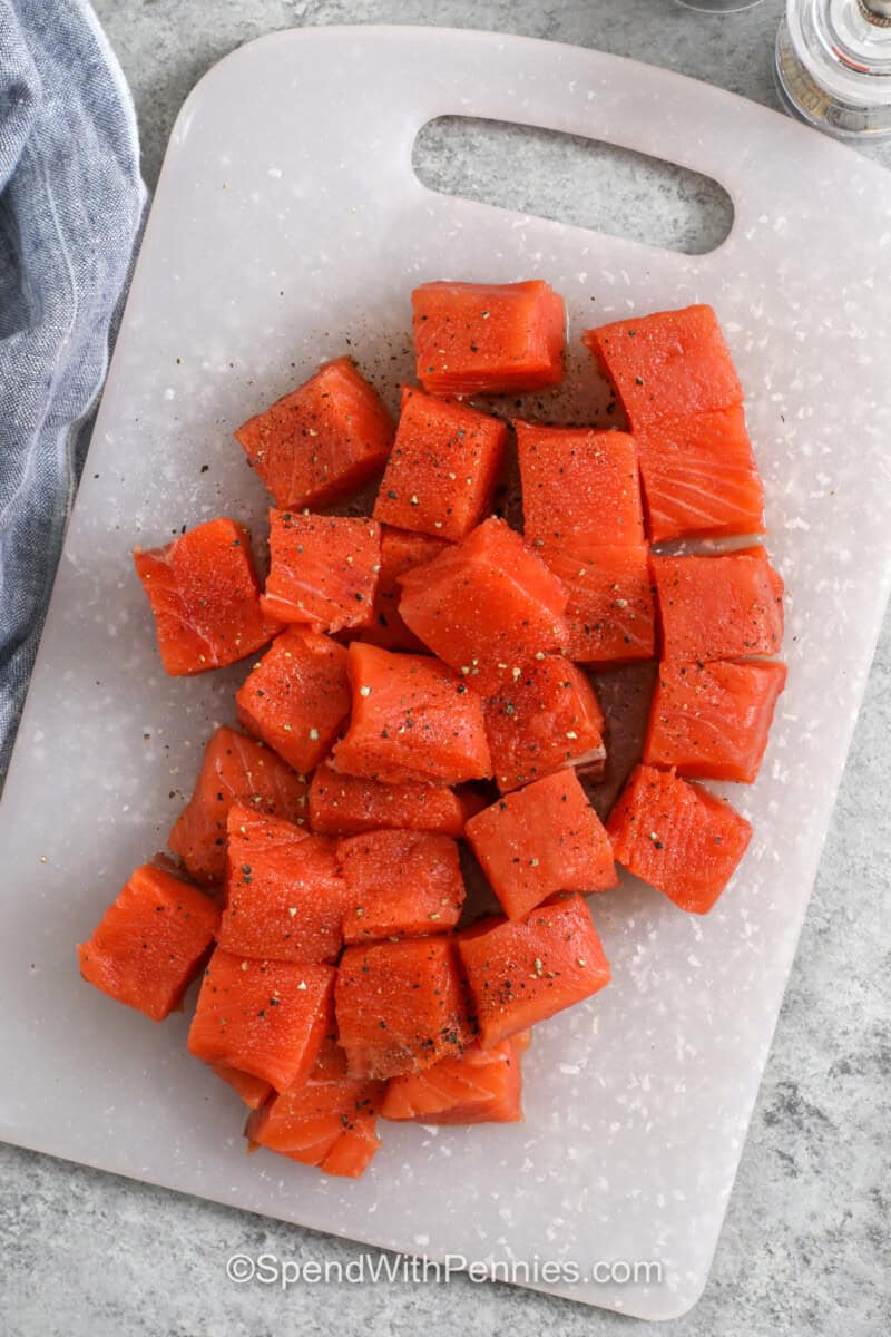 Uncooked salmon bites on a cutting board.